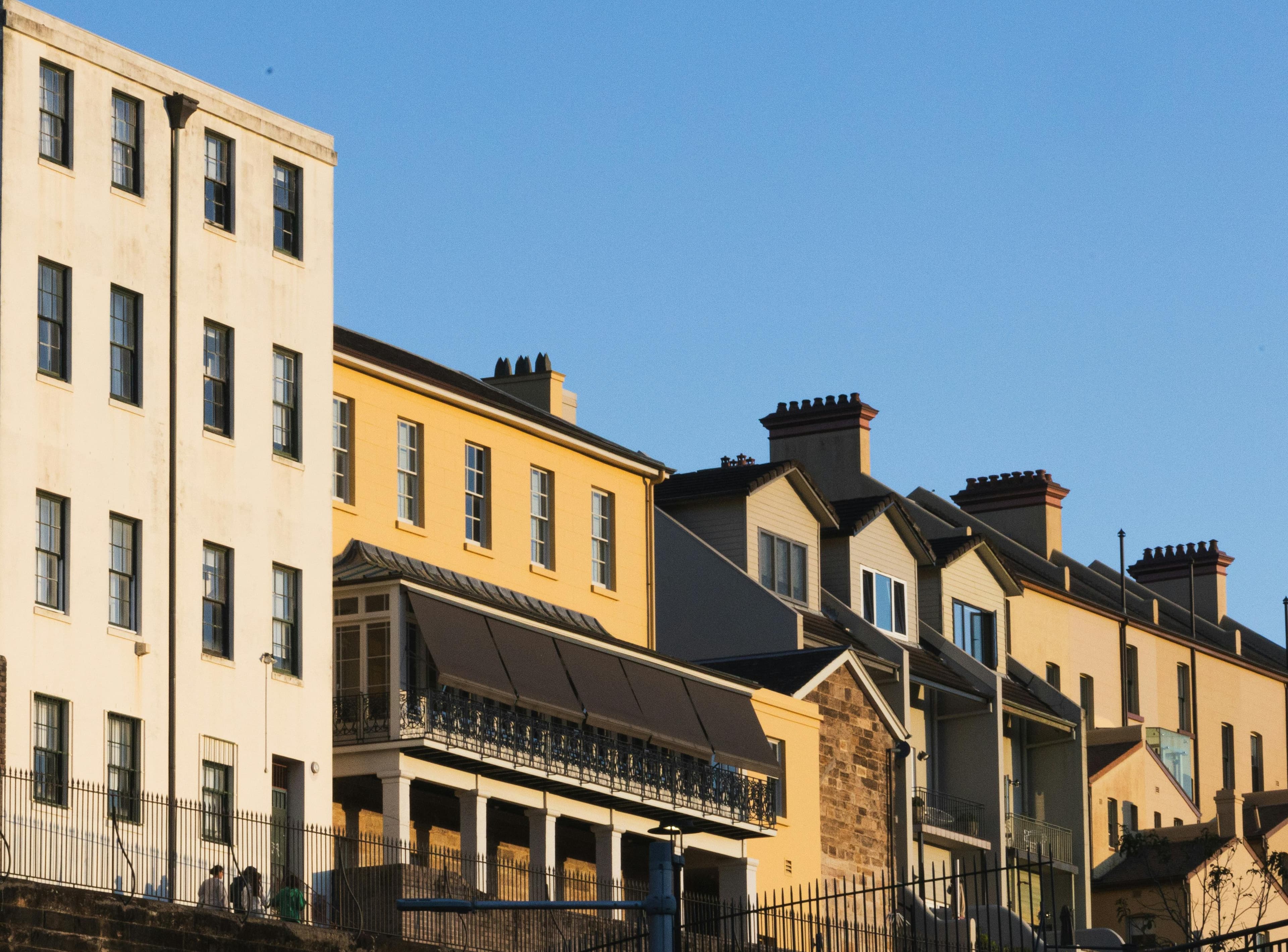 A row of restored Victorian terrace houses on a leafy inner-Melbourne street, with cast-iron lacework, painted facades and original brickwork